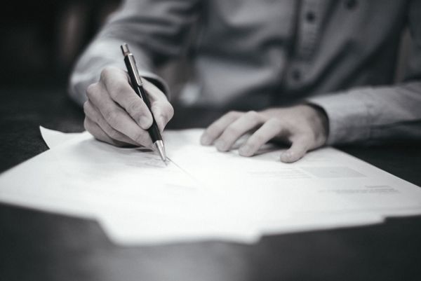 Close-up of someone writing on paper with a pen.